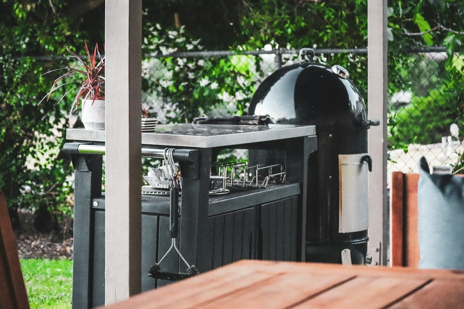 Grill with a side prep counter and potted plants in a simple outdoor area