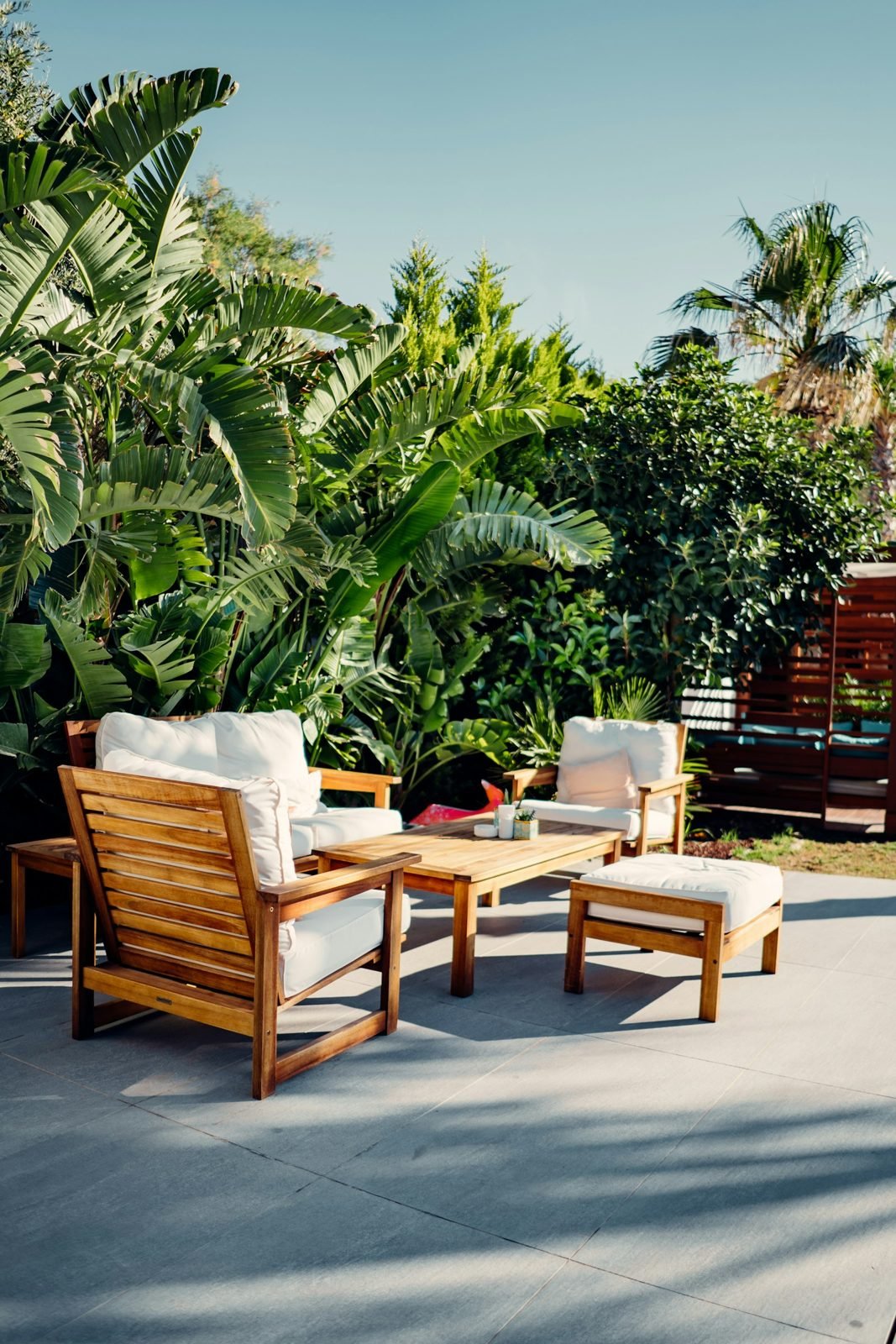Wooden outdoor table and chairs set surrounded by plants