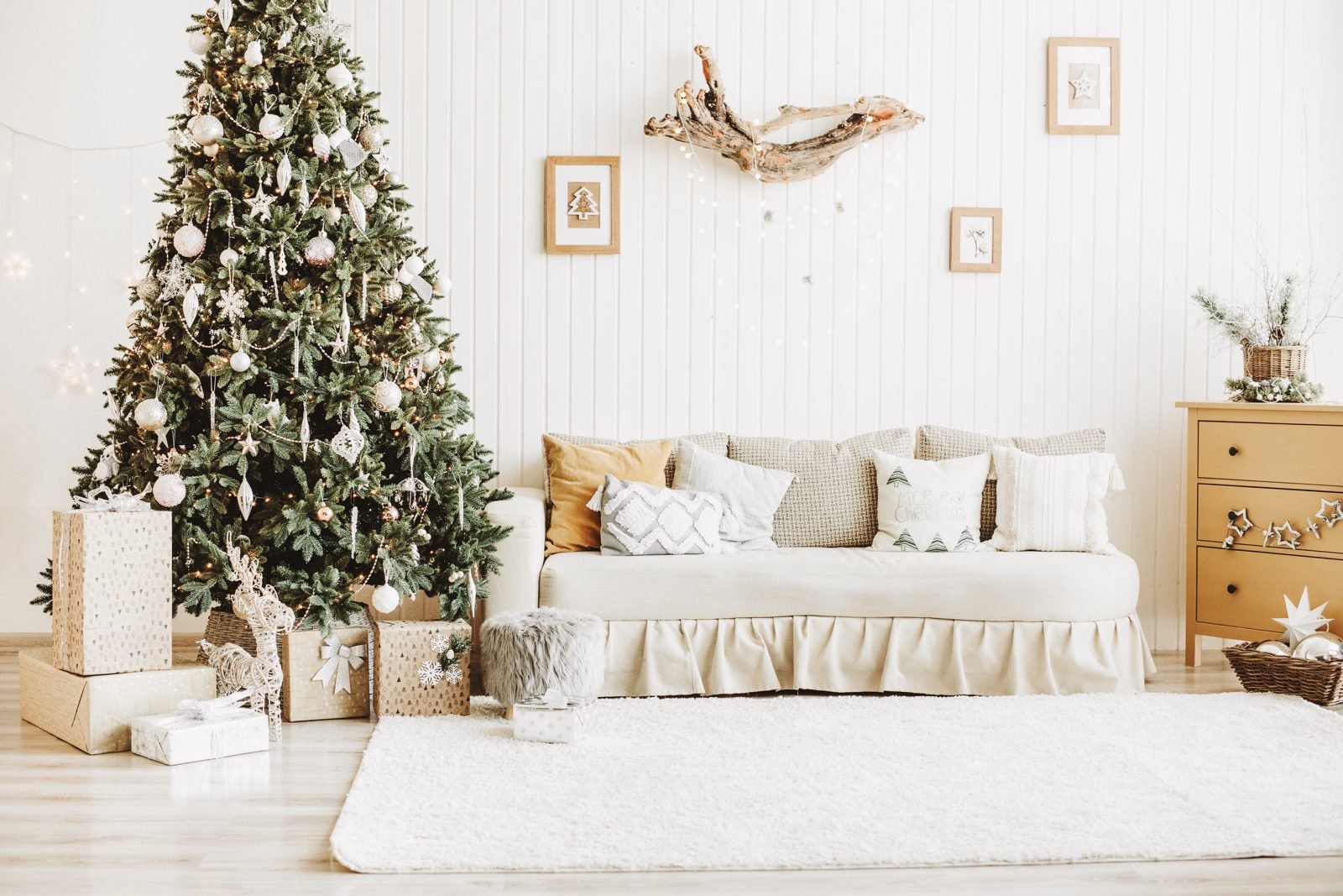 Sala decorada para o Natal com árvore, presentes e almofadas em tons neutros e vermelhos