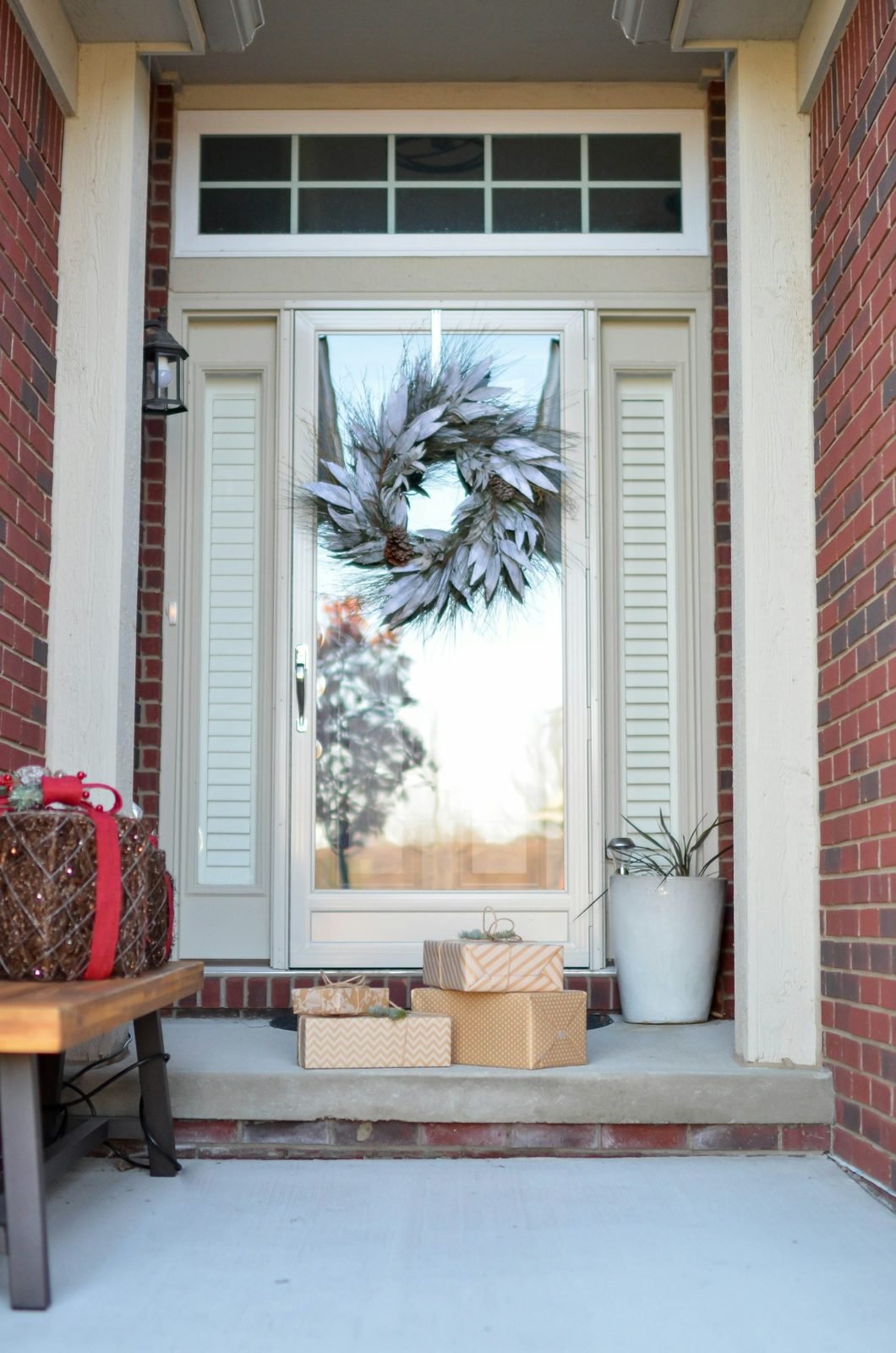 Front door with a pale wreath, wrapped gifts and a potted plant