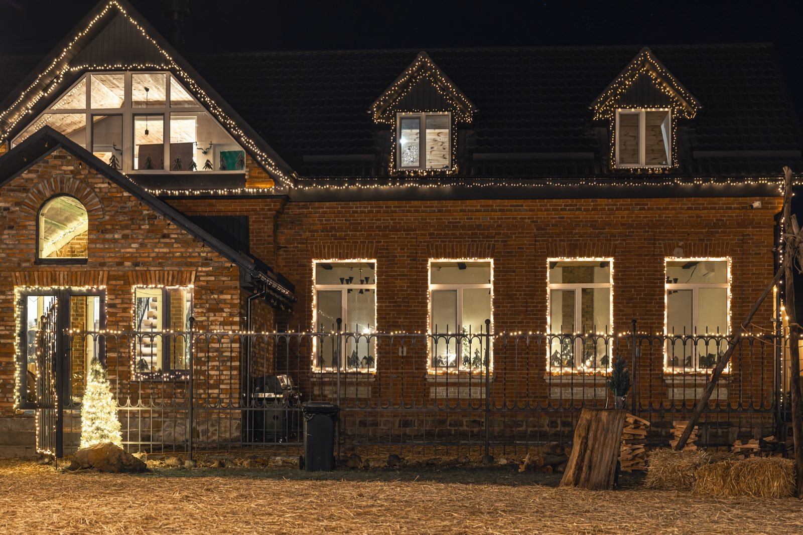 Brick house with windows, roofline and gate outlined in white lights at night