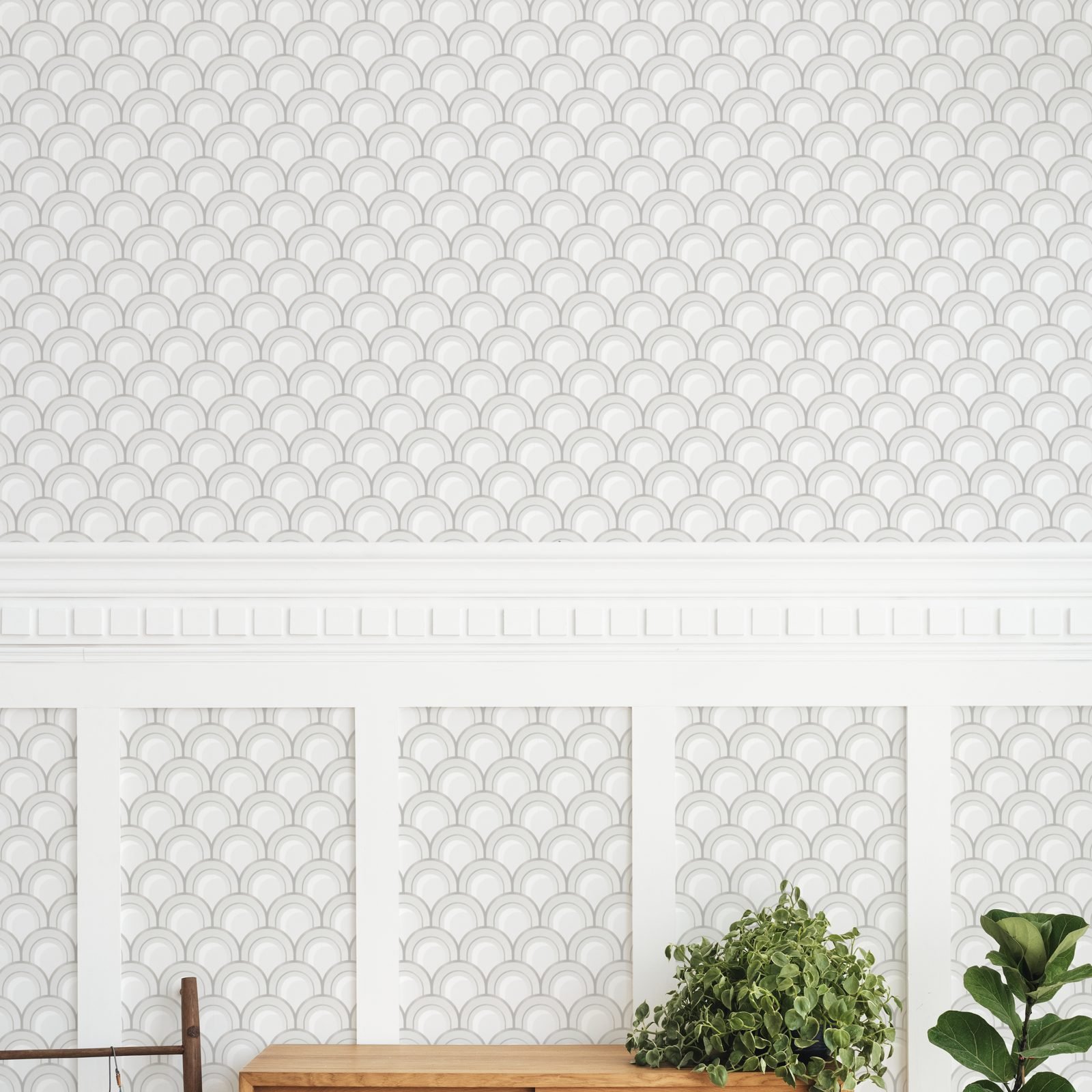 Wall with gray and white scallop-pattern wallpaper above white wainscoting